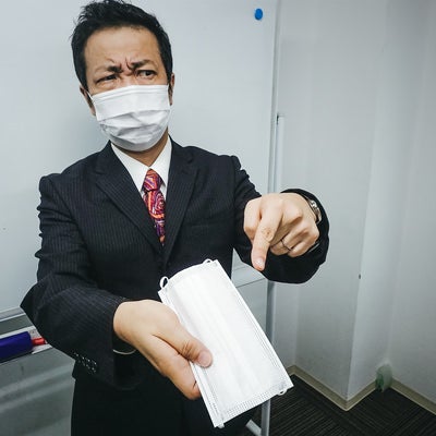 嫌な顔をしながらマスクを手渡しする会社員の写真