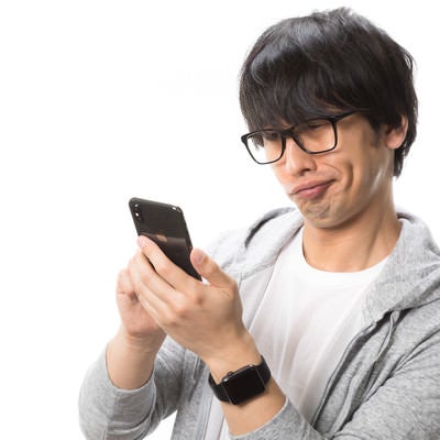 ポップアップ広告にいら立つスマホユーザー男性の写真