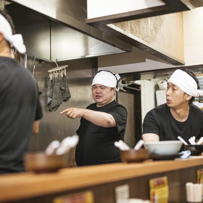 ラーメン屋の厨房で働く男性店員の写真