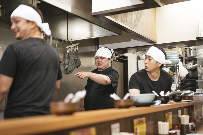 ラーメン屋の厨房で働く男性店員の写真