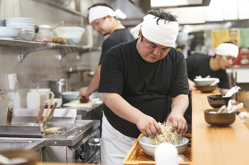 茹でる麺をほぐすラーメン屋の大将の写真