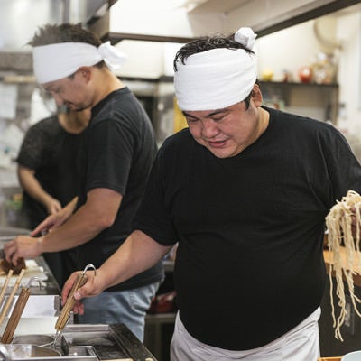 麺を片手にテボをチェックするラーメン屋の店主の写真