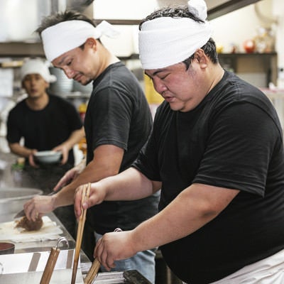 真剣な眼差しで厨房に立つラーメン店員の写真