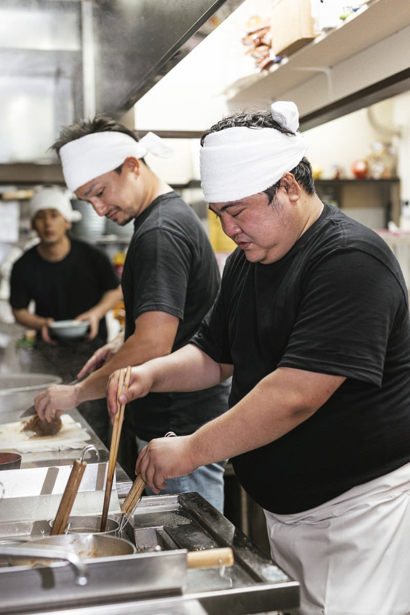 「真剣な眼差しで厨房に立つラーメン店員」の写真［モデル：段田隼人 Max_Ezaki 大川竜弥］