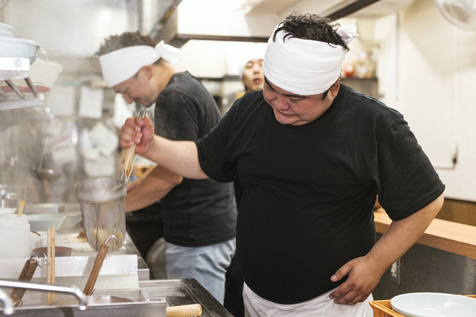 「力強く湯切りするラーメン店主の男性」の写真［モデル：段田隼人 Max_Ezaki 大川竜弥］