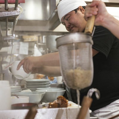 湯切りは任せて具をトッピングするラーメン店主の写真