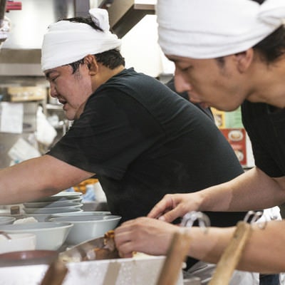 忙しい雰囲気が伝わるラーメン屋の厨房の写真