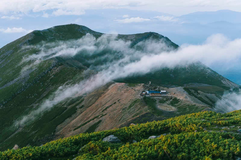 流れる雲に包まれる五ノ池小屋と継子岳の写真