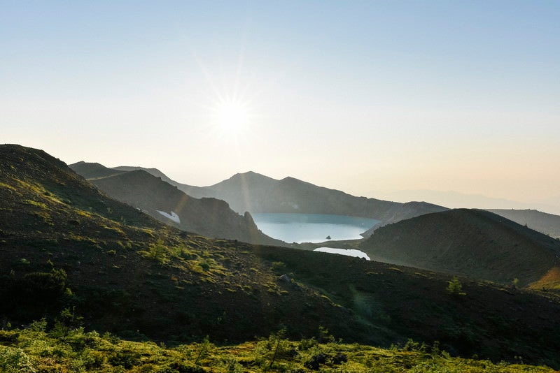 朝日を受ける草津白根山湯釜の写真