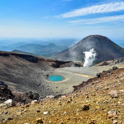 噴煙が上がる雌阿寒岳と青池の写真