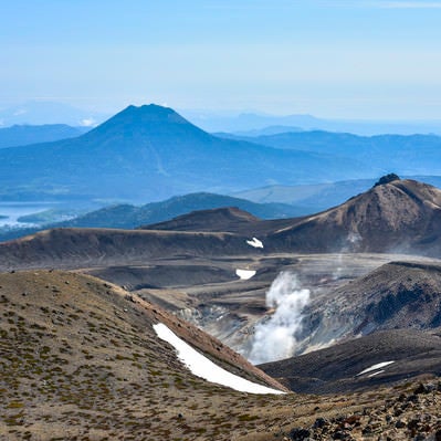 噴煙拭きあがる火山性の大地が広がる雌阿寒岳（めあかんだけ）の写真