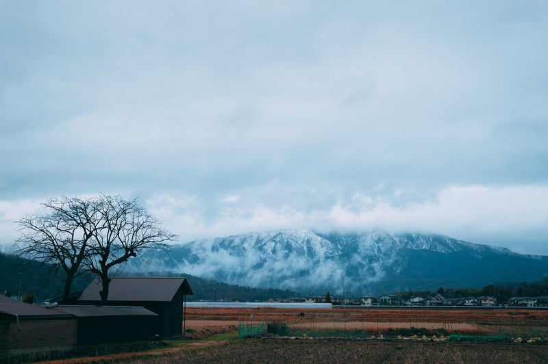 雲で頂上が隠れた山と麓の町の写真