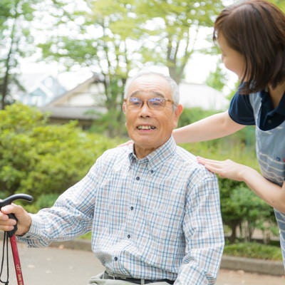 公園で日光浴を楽しむおじいさんと介護士の女性の写真