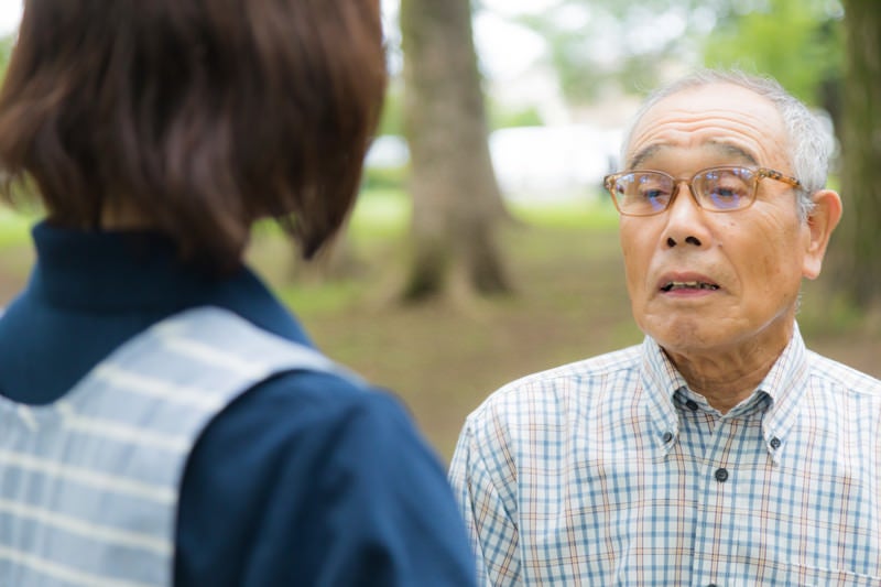 お爺さんの話を聞く介護士の写真