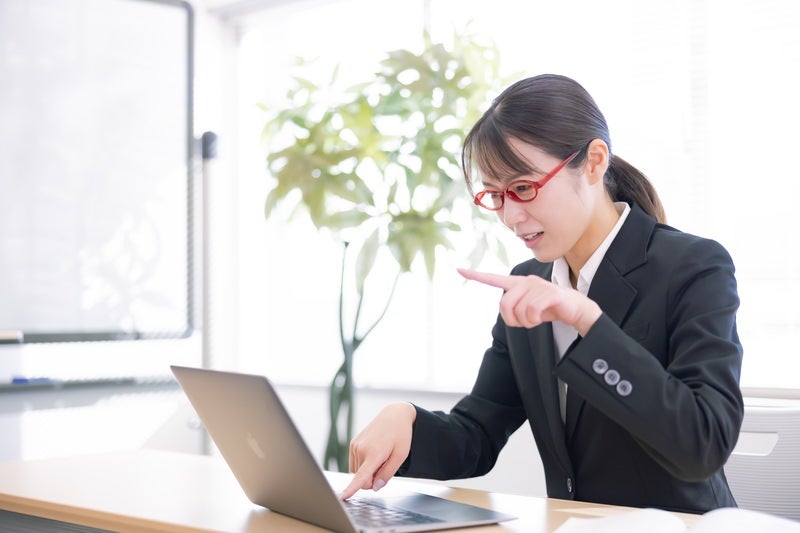 パソコン教室で学ぶ人差し指タイピングの女性の写真