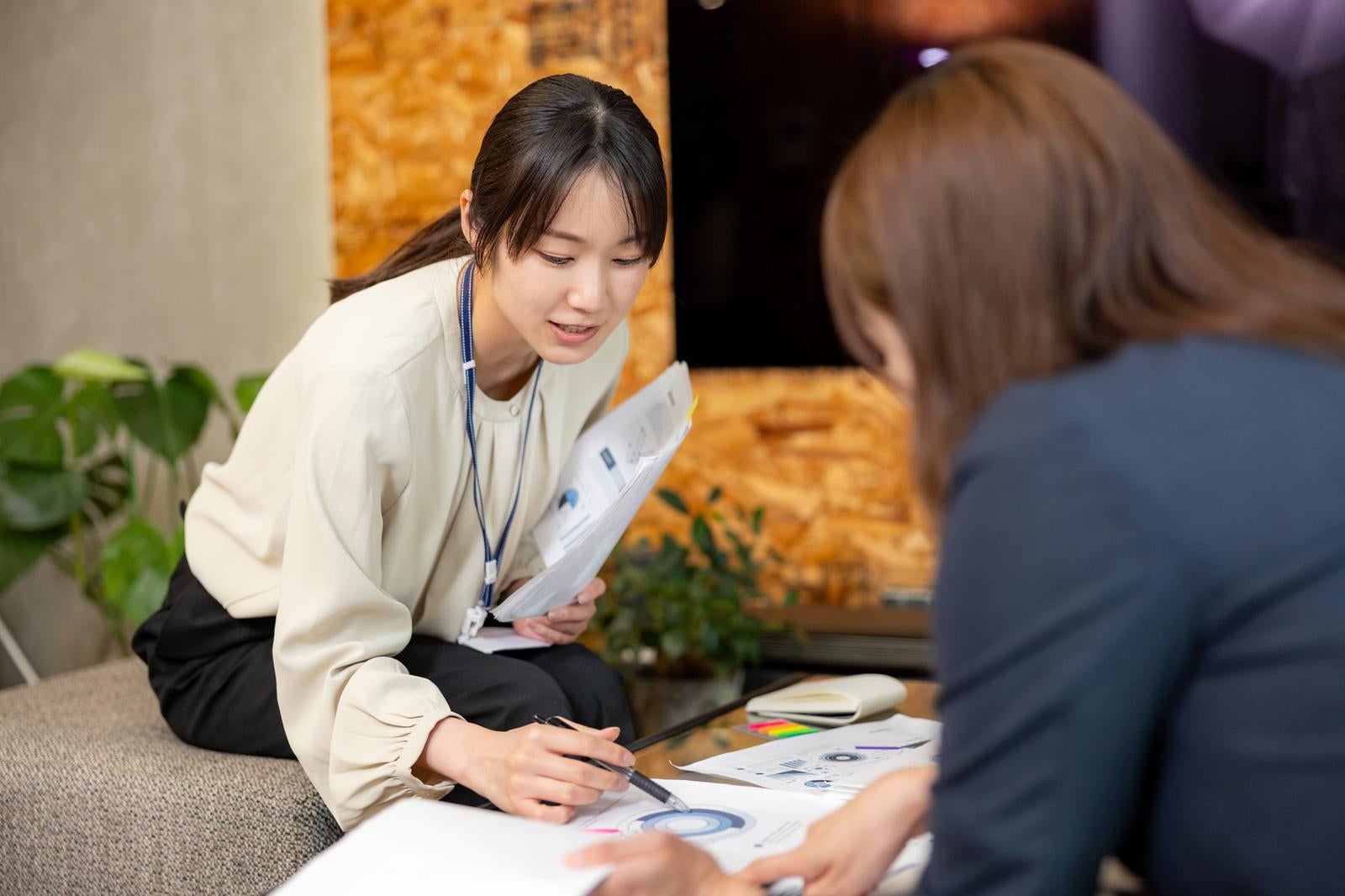 「二人の女性が資料を見ながら打ち合わせする様子」の写真［モデル：SAKI］