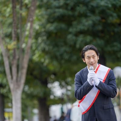 緑豊かな公園で演説する若い男性政治家の写真