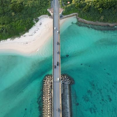 透き通る海と白い砂浜に架かる橋の写真