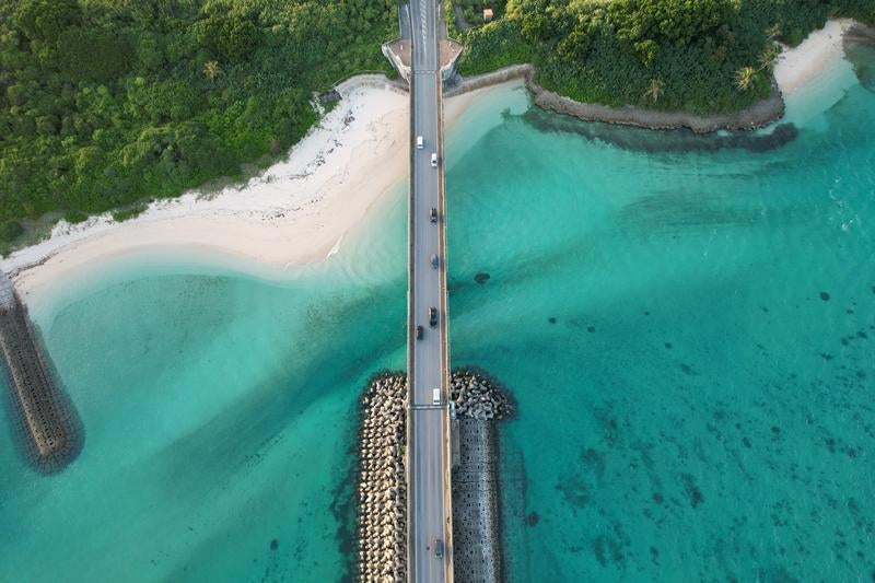 透き通る海と白い砂浜に架かる橋の写真