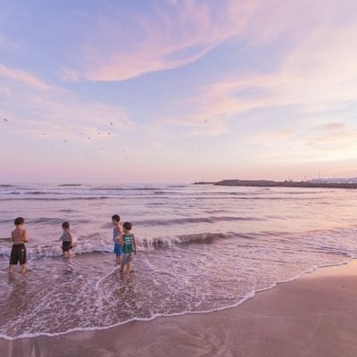 夕暮れに浜辺で遊ぶ子どもたちの写真