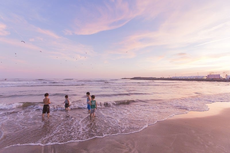 夕暮れに浜辺で遊ぶ子どもたちの写真