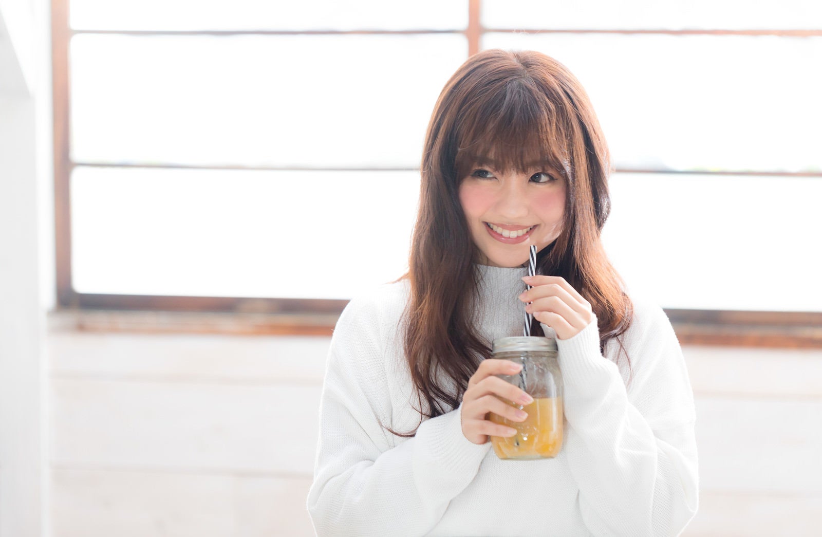 「笑顔でスムージーを飲む女性」の写真［モデル：河村友歌］