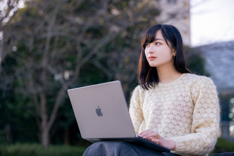 公園でネット検索する女性の写真