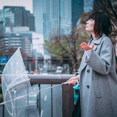 雨が止んだか確かめる女性の写真