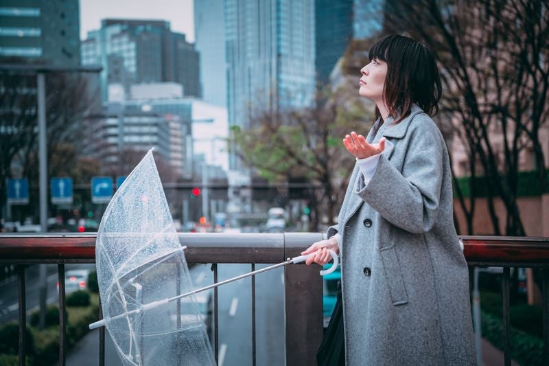 雨が止んだか確かめる女性の写真