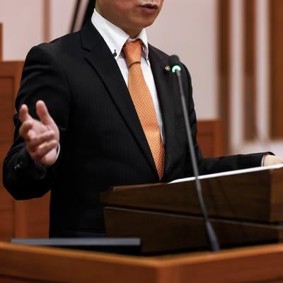 演壇して手振りで語る議員の姿の写真