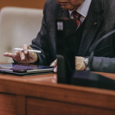 おぼつかないながらもタブレットを使う津山市議会の議員の写真