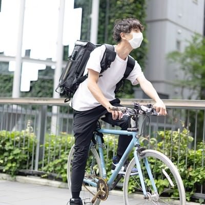 自転車に乗って配達する男性の写真