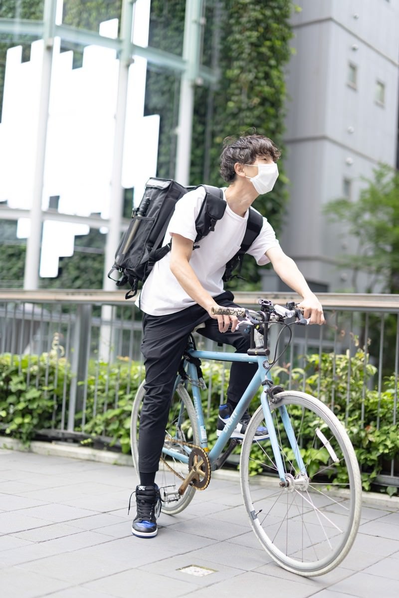 自転車に乗って配達する男性の写真