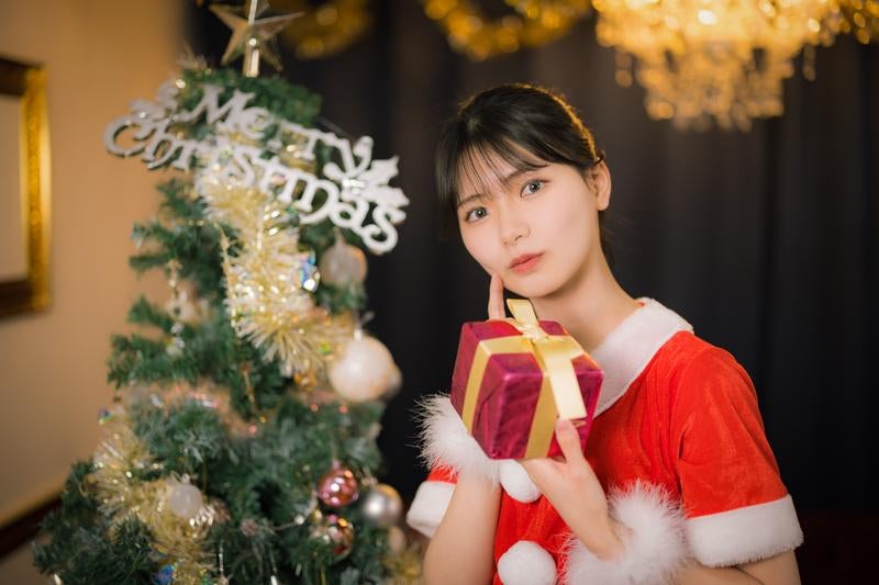 クリスマスツリーとサンタコスの彼女とプレゼントの写真