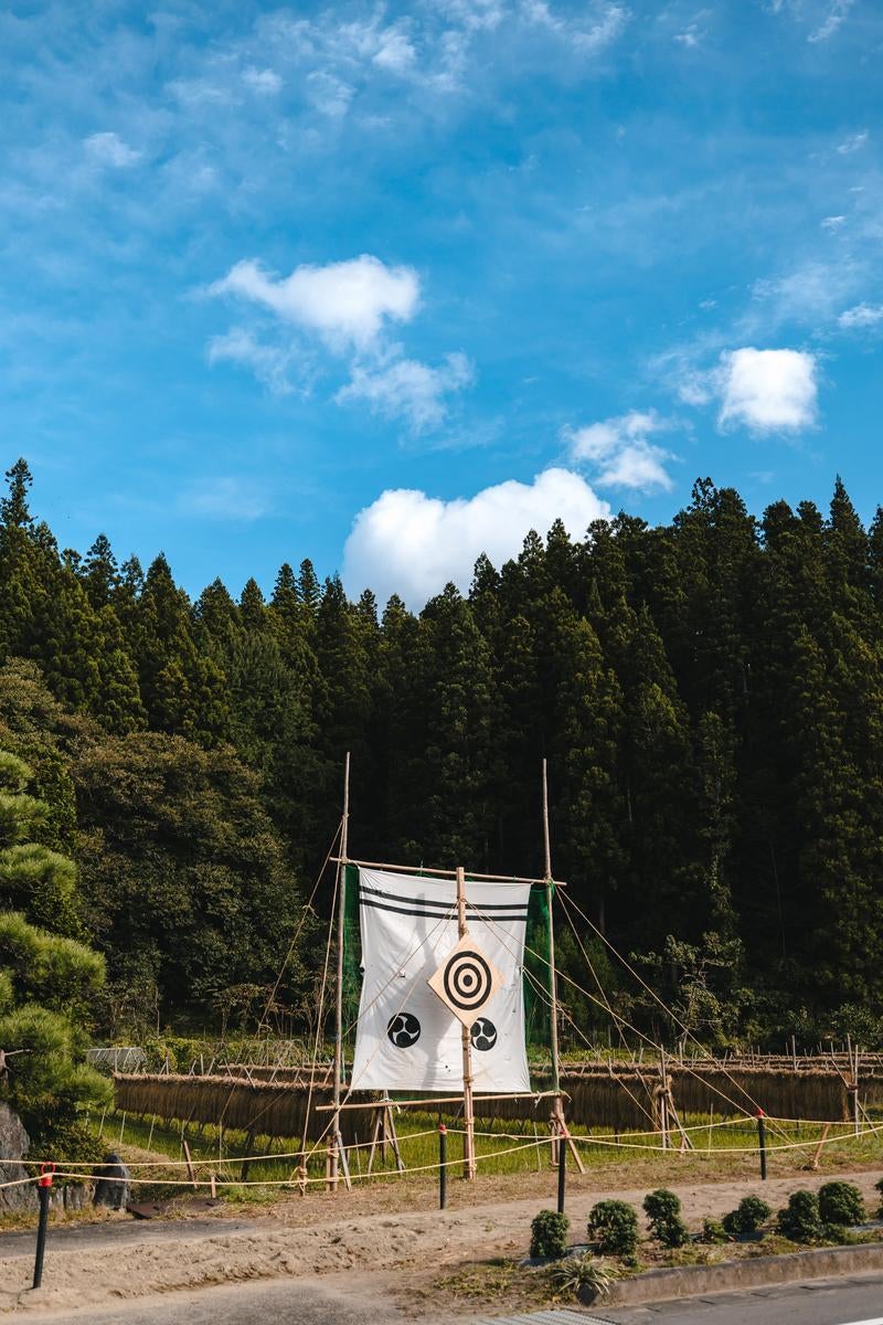 青空の下の稲架掛けと流鏑馬の的の写真