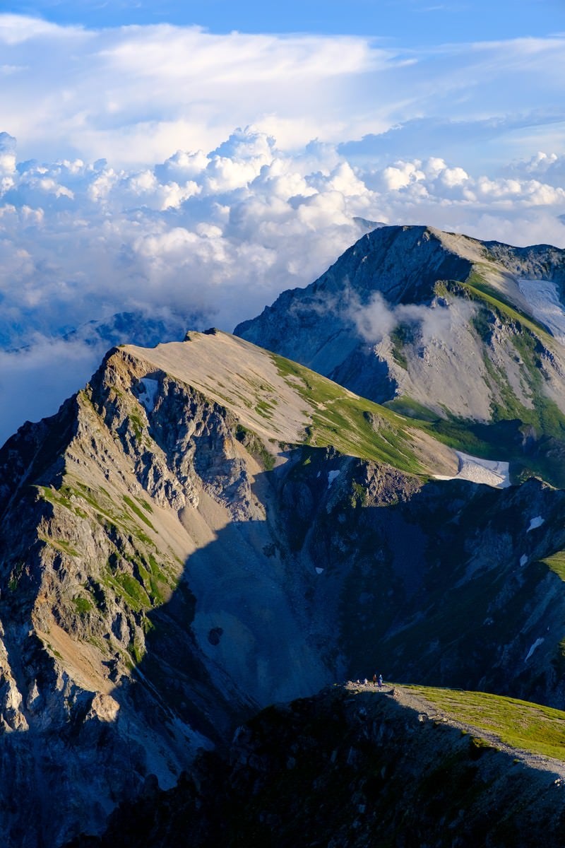 登山道を歩く登山者と杓子岳の写真