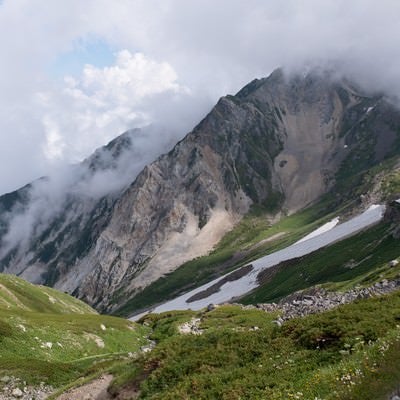 白馬岳（しろうまだけ）の雪渓と沸き立つ雲間に見える山々（白馬岳）の写真