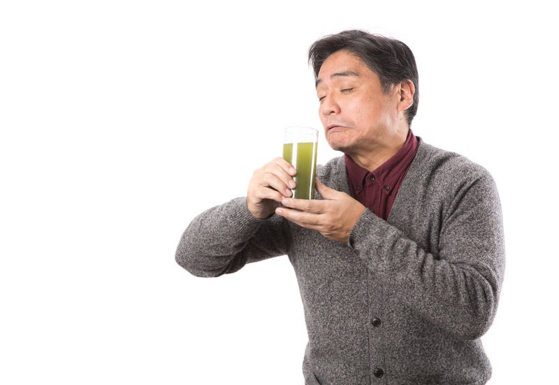 苦手な青汁をすすり飲むお父さんの写真