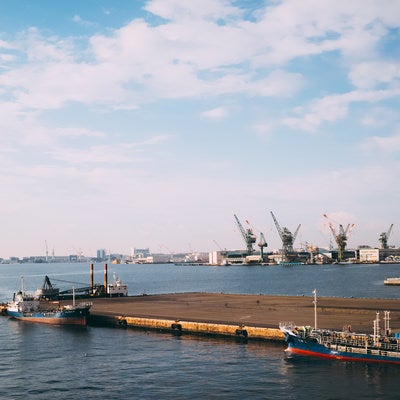 日が陰った空と船が停泊している港の写真