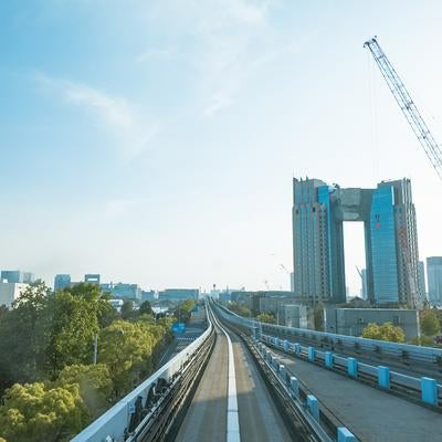 大型クレーンやビルが望む都市風景とゆりかもめの軌道の写真