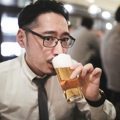 乾杯前にこっそり飲む男性の写真