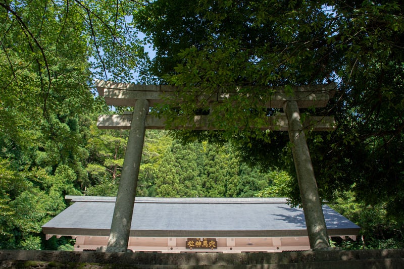 九頭竜湖畔沿いの道から見上げる九頭竜ダム建設に伴い水没した集落の神社を合祀した穴馬神社の鳥居と奥に見える拝殿の写真