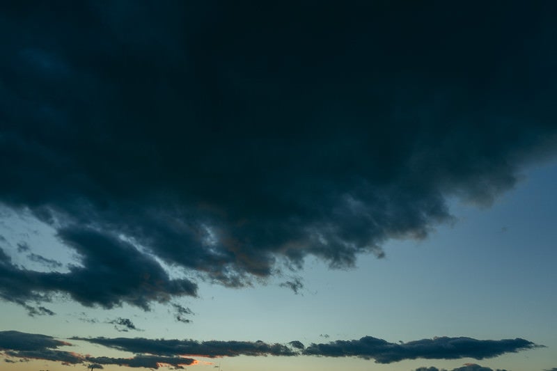 少し赤みの残る黒い雲が覆い始めた夕焼けの空の写真