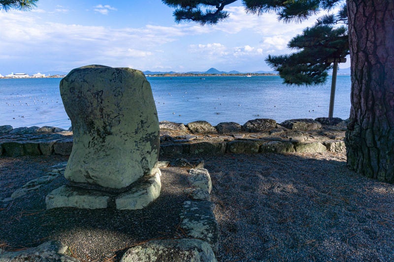 境内の松の木陰に建つ「鎖あけて月さし入よ浮み堂」と刻まれた松尾芭蕉の句碑の写真