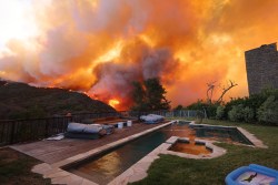 A brush fire burns near homes in Pacific Palisafes, California on January 7, 2025. A fast-moving brushfire in a Los Angeles suburb burned buildings and sparked evacuations Tuesday as "life threatening" winds whipped the region. More than 200 acres (80 hectares) was burning in Pacific Palisades, a upscale spot with multi-million dollar homes in the Santa Monica Mountains, shuttering a key highway and blanketing the area with thick smoke. (Photo by David Swanson / AFP) (Photo by DAVID SWANSON/AFP via Getty Images)