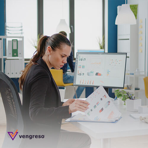 A woman is using sales tools to analyze a document at her desk.