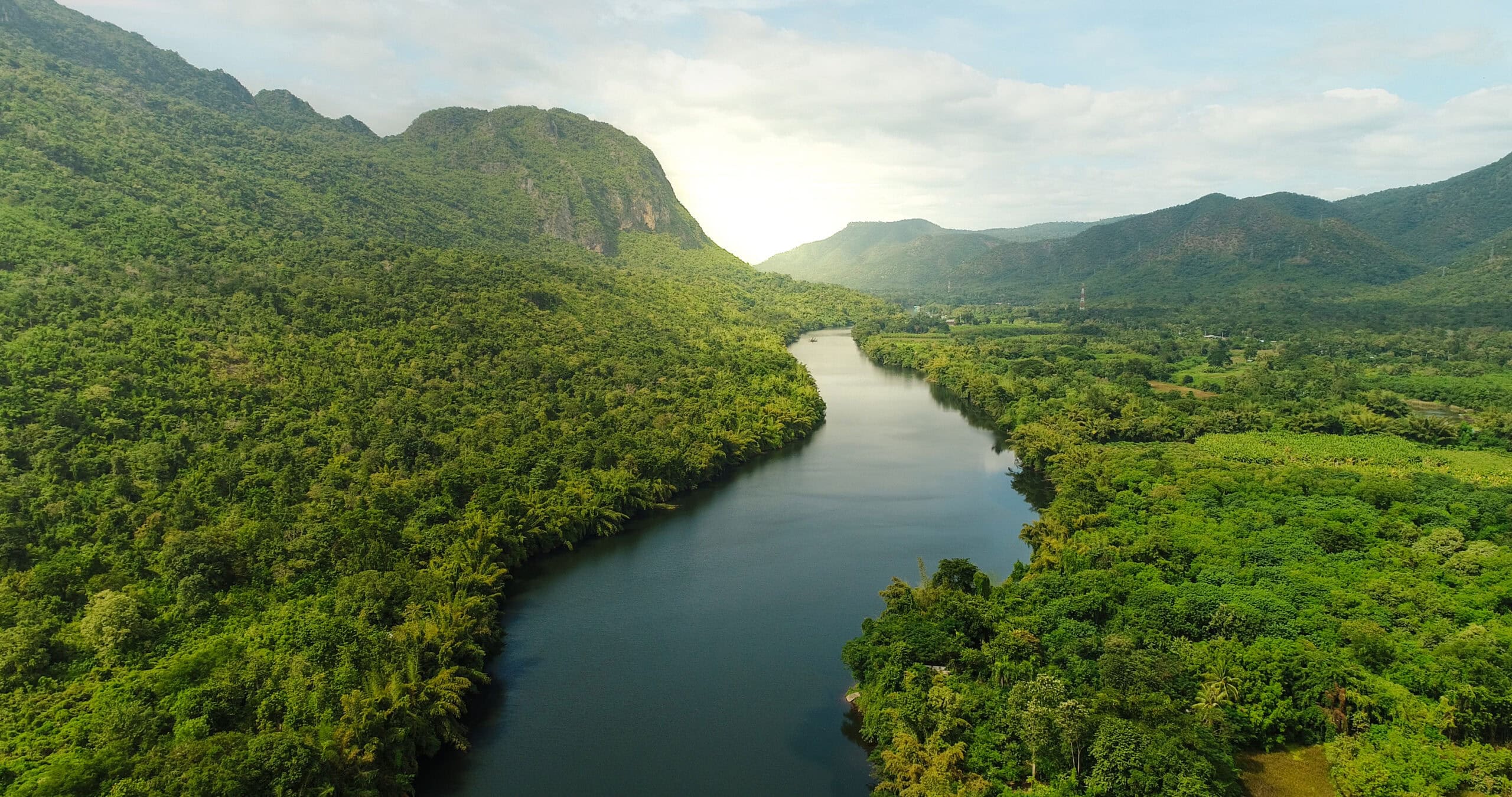 Beautiful natural scenery of river in southeast Asia tropical green forest with mountains in background, aerial view drone shot