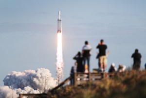 People watch as the SpaceX Falcon Heavy rocket lifts off. 