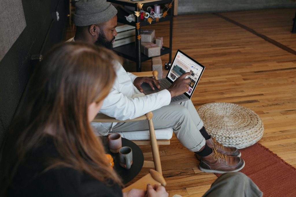 Looking over the shoulder of a man and woman sitting in a room with wooden floors while working