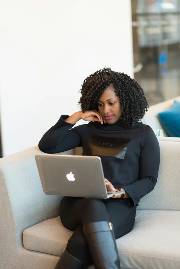 Coach for Women of Color Founders- Black woman sitting on a couch with a laptop